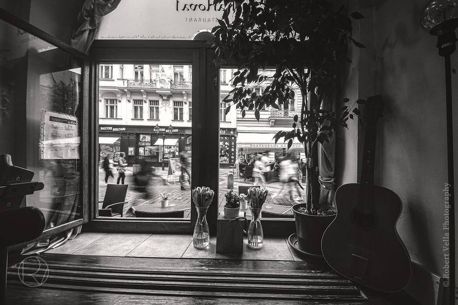 The inside of a café looking out onto the street, a guitar leaning in the corner
