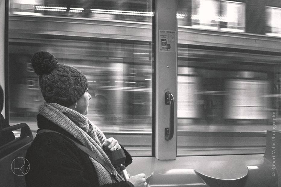 A traveller in a woollen hat on a tram, the city outside blurred past the window