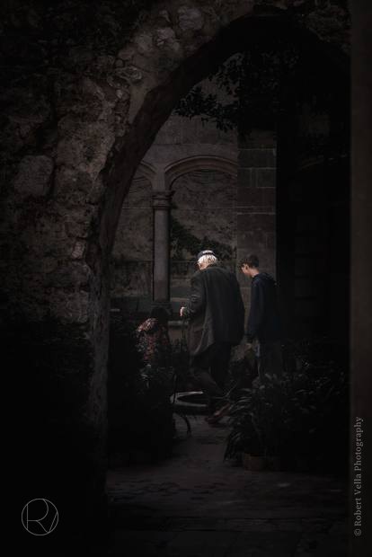Two figures under a stone archway in the last of the evening light