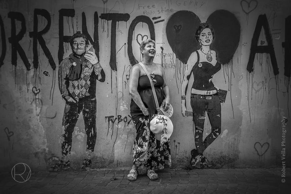 A woman standing in front of a painted wall, posing with the figures sprayed on it